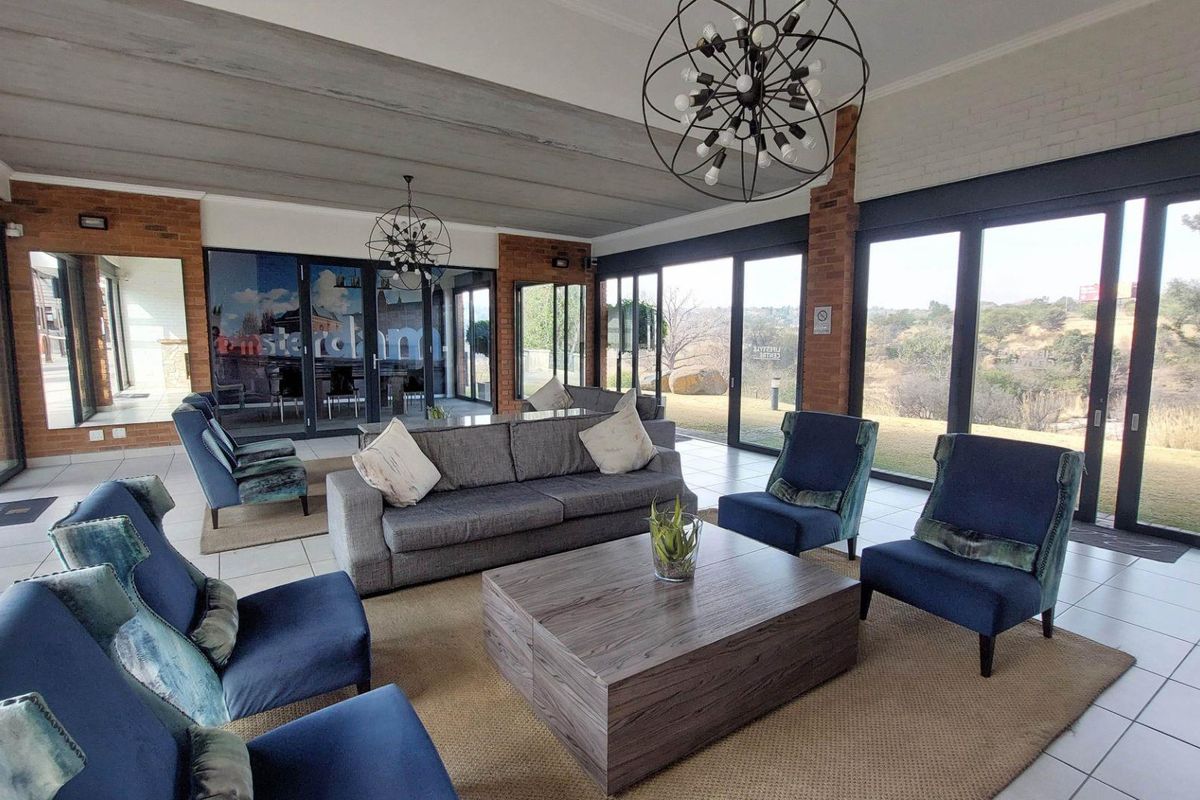 Spacious living area featuring exposed brick accents, large sliding glass doors providing natural light, and modern pendant lighting with scenic outdoor views.