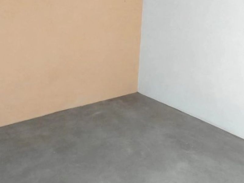 An empty utility space featuring a concrete floor and exposed timber ceiling beams, offering a blank canvas for renovation or storage use.