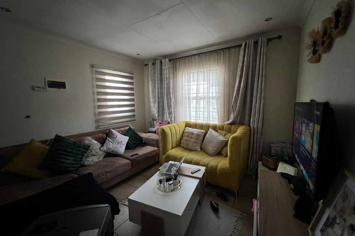 A cozy living room featuring tiled flooring, recessed downlighting, and window treatments, providing a functional and comfortable space for relaxation.