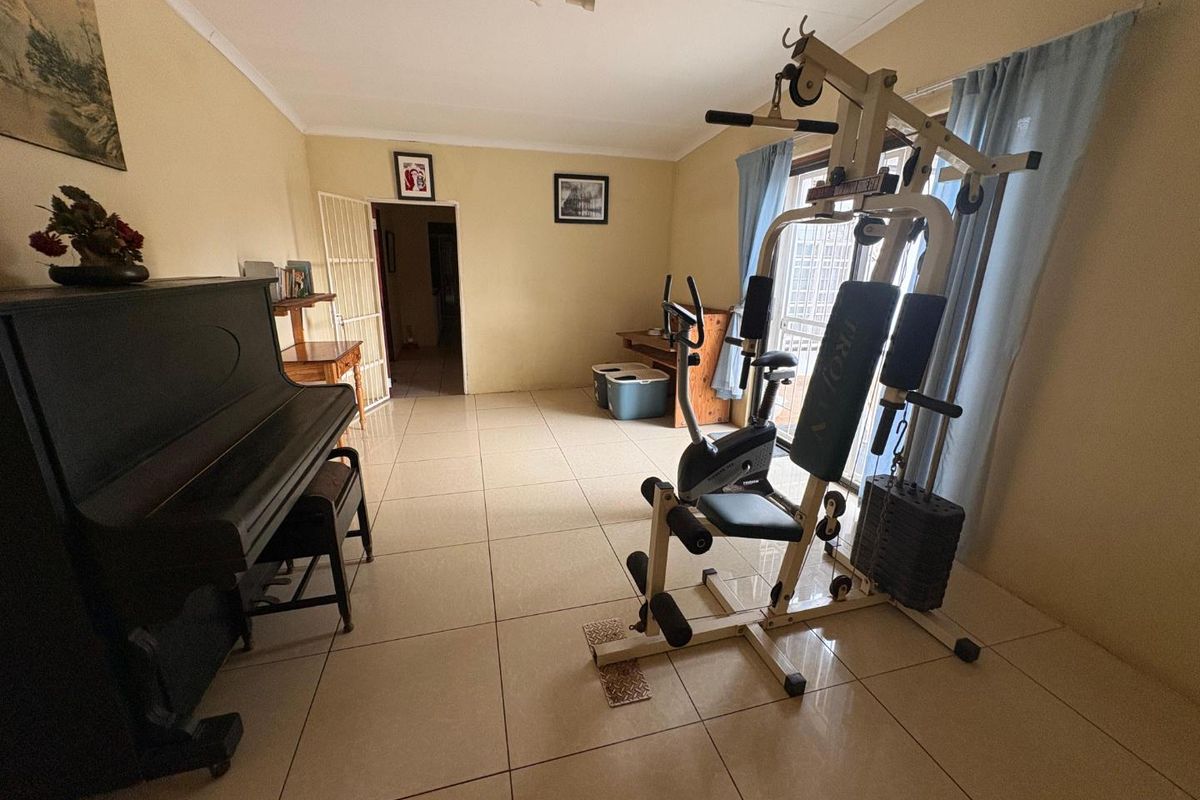 A multi-purpose room featuring large format floor tiles, neutral wall finishes, and access to an outdoor area through sliding glass doors.