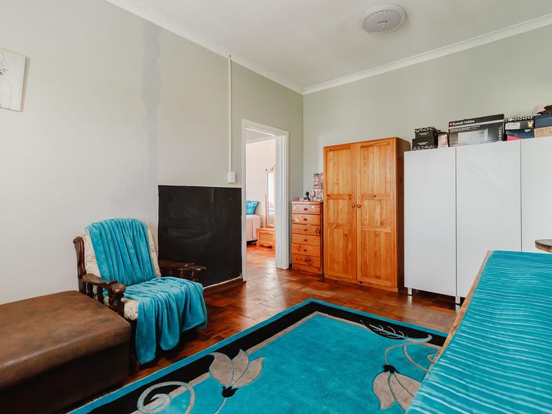 A bedroom featuring original parquet flooring and coved cornicing, currently requiring cosmetic updates to the wall finishes and electrical fixtures.