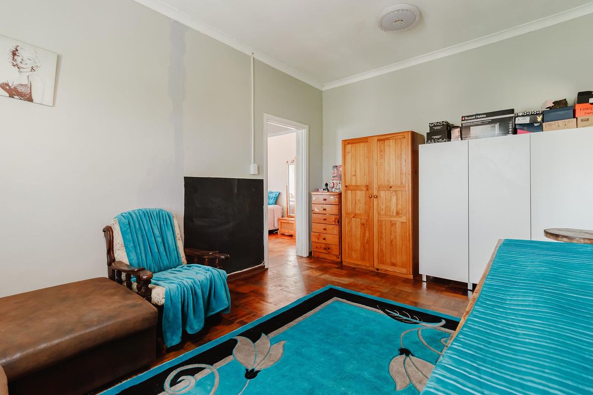 A bedroom featuring original parquet flooring and coved cornicing, currently requiring cosmetic updates to the wall finishes and electrical fixtures.