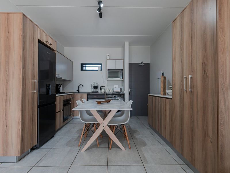 Modern kitchen featuring wood-grain cabinetry, integrated appliances, tiled flooring, and a functional layout with ample storage space.