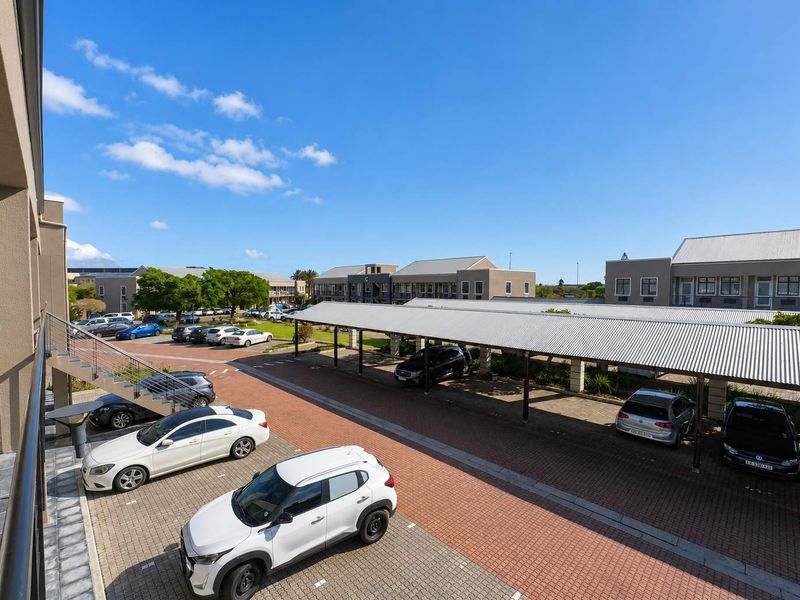 Elevated view of a well-maintained office complex parking area featuring covered parking bays, paved driveways, and external building access.