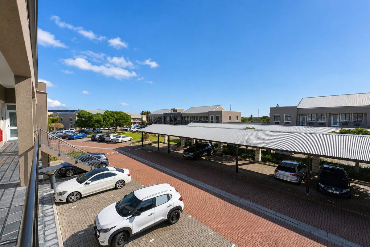 Elevated view of a well-maintained office complex parking area featuring covered parking bays, paved driveways, and external building access.