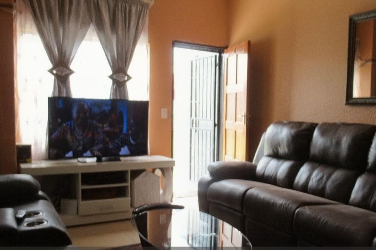 A living room area featuring tiled flooring and direct access to the exterior through a security gate.