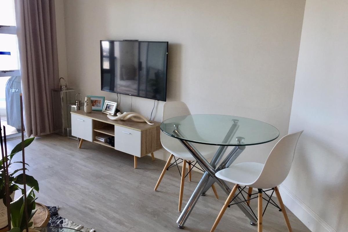 A bright living area featuring modern laminate flooring and a sliding glass door providing access to the outdoor space.