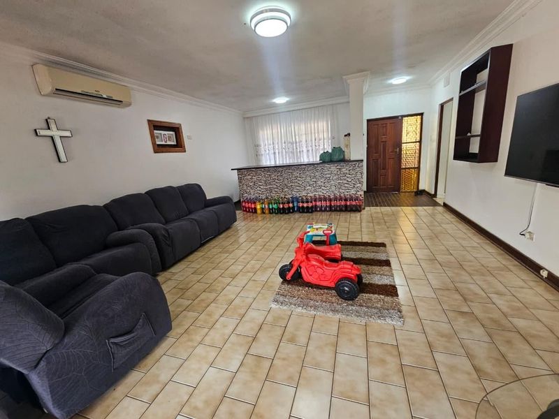 Spacious living area featuring tiled flooring, a built-in bar, and a wall-mounted air conditioning unit.