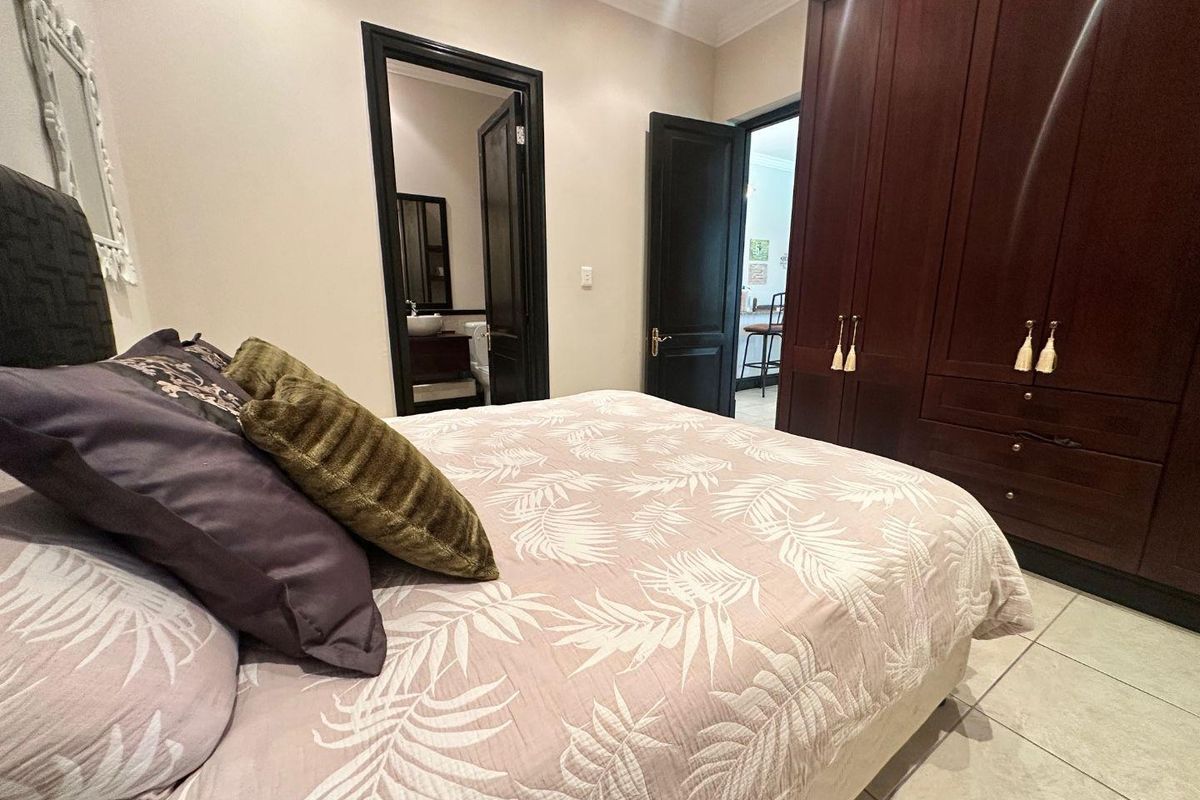A well-maintained bedroom featuring built-in dark wood cabinetry and an en-suite bathroom with tiled flooring.