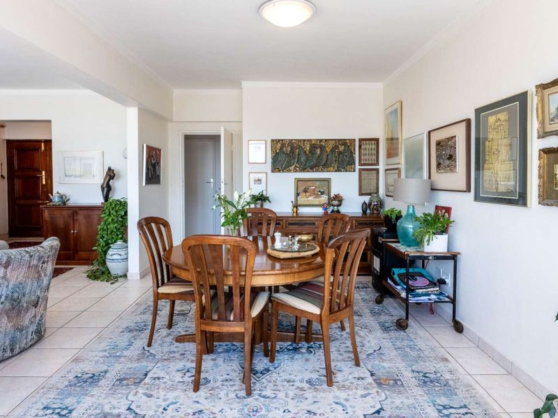 A well-lit dining area featuring neutral tiled flooring and an open-plan layout connecting to the adjacent living space.