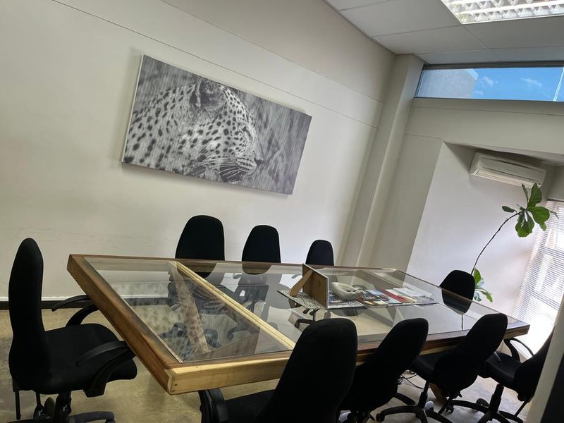 A professional office meeting room featuring a suspended ceiling, clerestory windows for natural light, and a wall-mounted air conditioning unit.