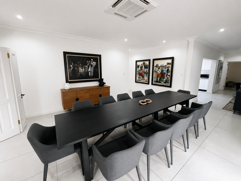A spacious and modern dining room featuring sleek tiled flooring, recessed ceiling lighting, and a built-in ceiling air conditioning unit.