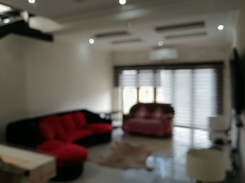 A living room featuring tiled flooring, recessed ceiling lighting, and roller blinds, with an installed air conditioning unit.