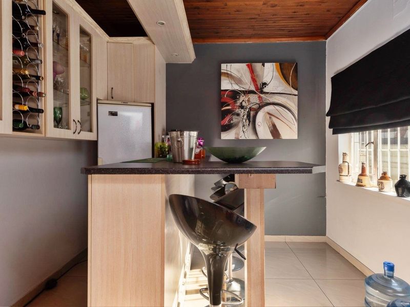 A dedicated bar area featuring built-in cabinetry, a wine rack, a breakfast bar counter, and a timber ceiling.