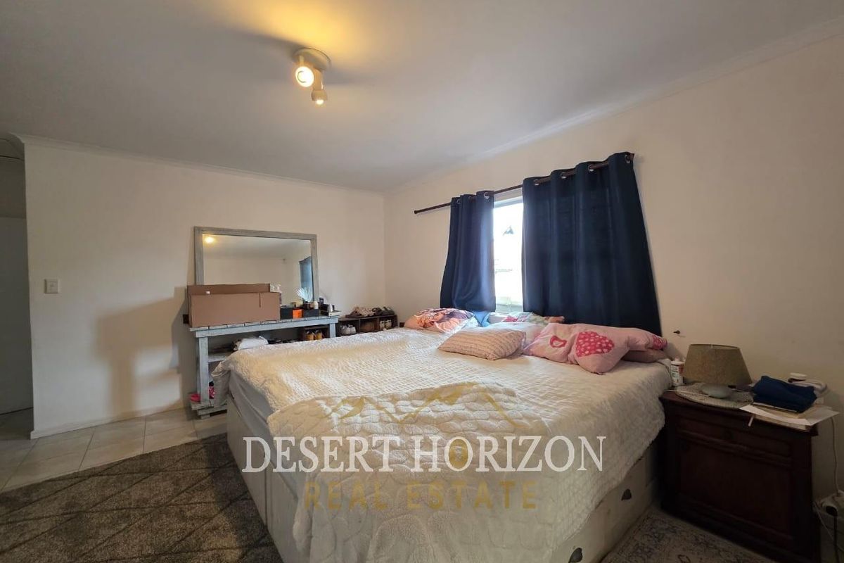 A functional bedroom featuring tiled flooring, a central ceiling light fixture, and a window with curtain rod.