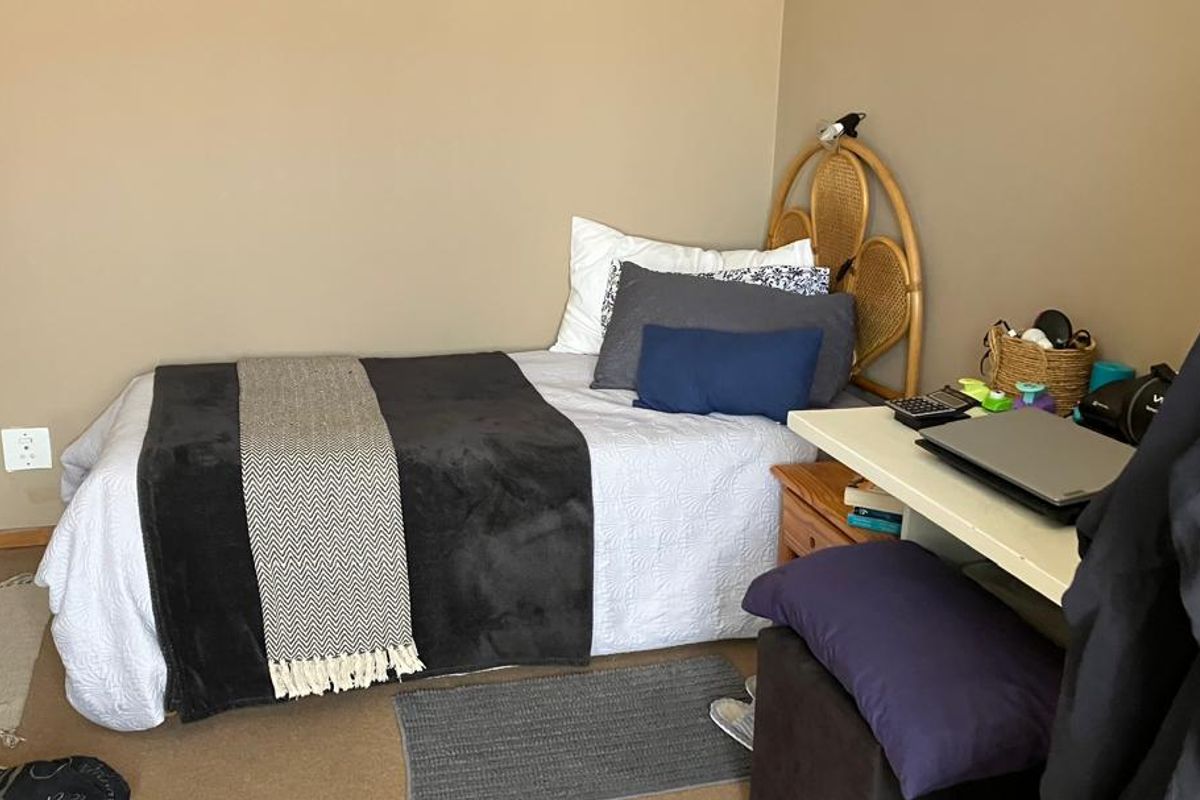 A functional bedroom featuring neutral wall tones, carpeted flooring, and standard electrical fixtures, providing a comfortable and practical living space.