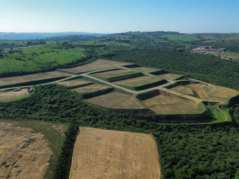 Aerial view of a developed industrial land site featuring terraced platforms and internal road infrastructure surrounded by natural landscape.