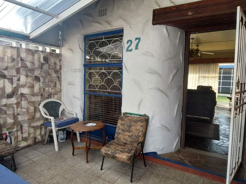 Covered patio area featuring tiled flooring, brick walling, and a security gate entrance, providing a functional outdoor transition space.