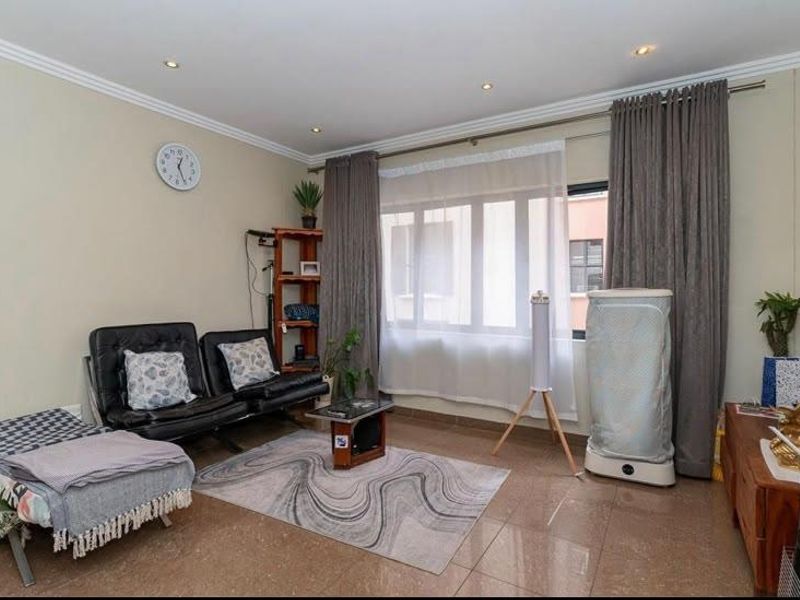 A living room featuring tiled flooring, recessed downlighting, and large windows with curtain treatments.