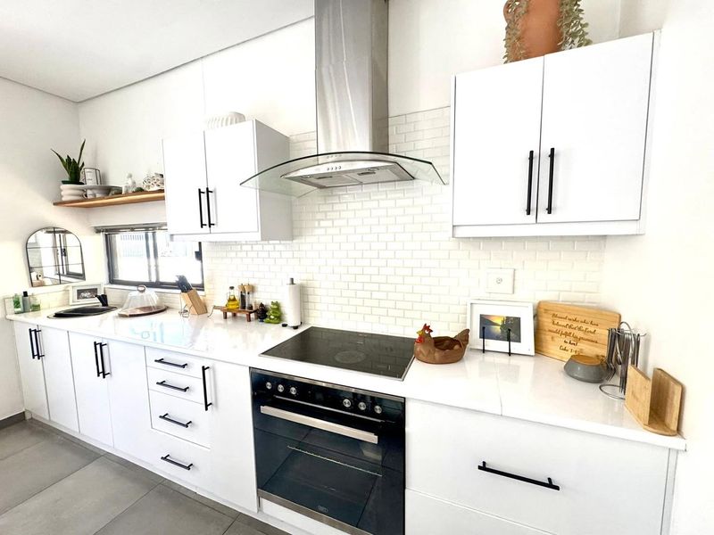 Modern kitchen featuring white cabinetry, subway tile backsplash, quartz countertops, and integrated stainless steel appliances.