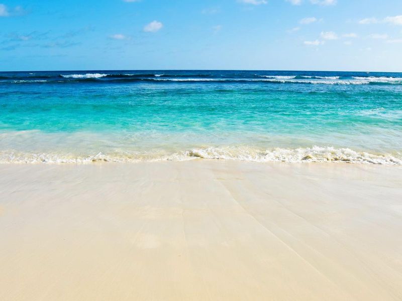 A scenic view of the pristine sandy beach and turquoise ocean waters, highlighting the natural coastal beauty surrounding the property.