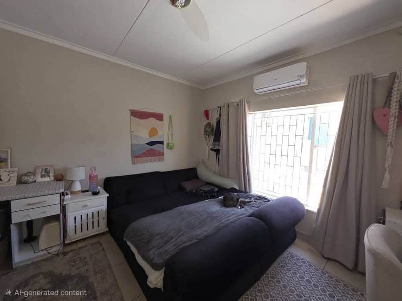 A bedroom featuring a wall-mounted split-system air conditioner, a ceiling fan, and a window fitted with security bars.
