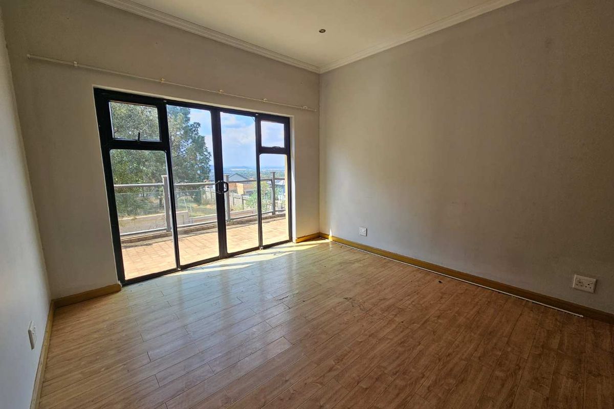 An empty bedroom featuring laminate flooring, recessed lighting, and a large sliding glass door providing access to an outdoor balcony area.