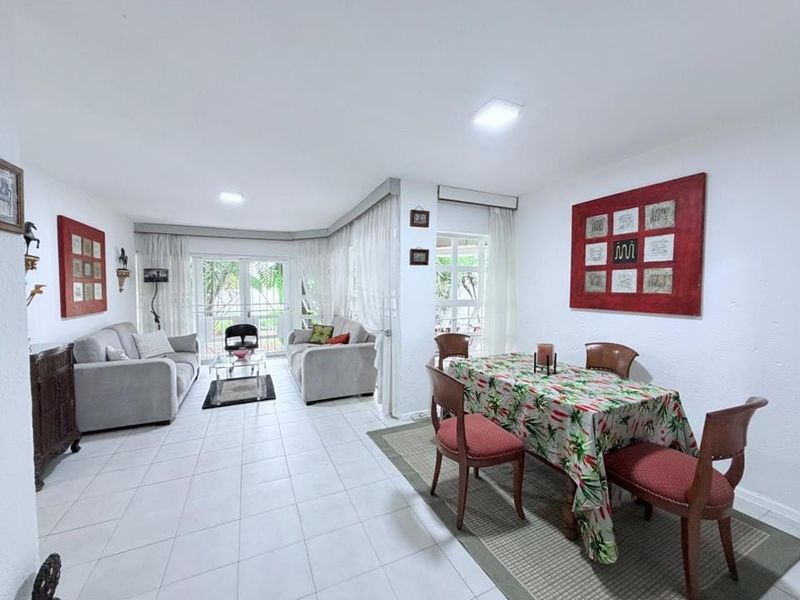 Open-plan living and dining area featuring neutral tiled flooring, recessed lighting, and large sliding glass doors providing access to the outdoor space.