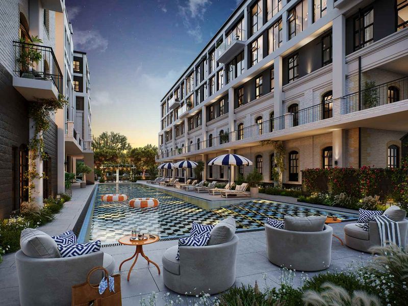 A beautifully landscaped outdoor pool area featuring a modern swimming pool, paved terrace, and balconies overlooking the communal space.