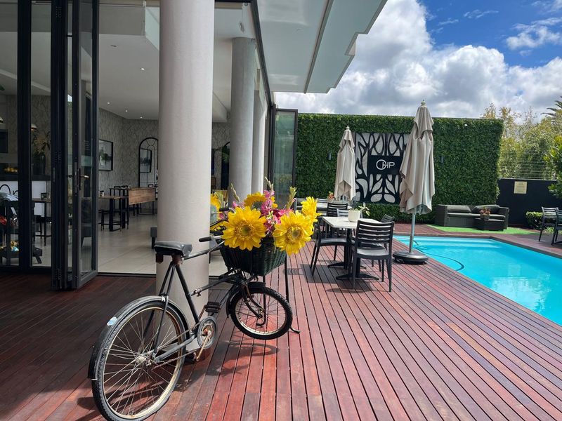 Outdoor pool area featuring timber decking, a vertical garden wall, and seamless indoor-outdoor flow through large bi-fold doors.