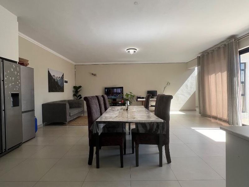 Spacious open-plan living and dining area featuring large format floor tiles and sliding glass doors providing ample natural light.