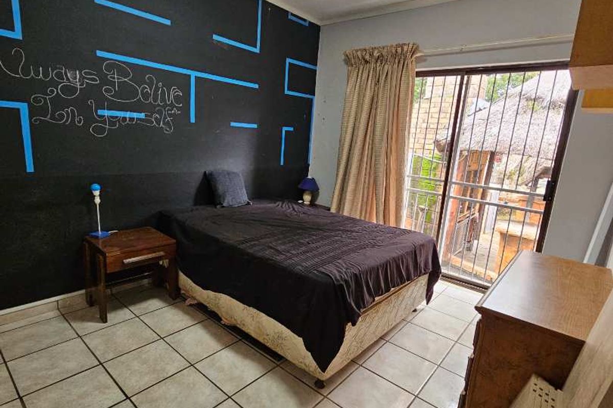 A bedroom featuring tiled flooring, a feature wall with decorative paint, and sliding glass doors providing access to an outdoor area.