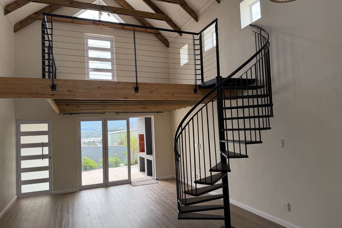Spacious living area featuring a mezzanine level, exposed timber trusses, a modern spiral staircase, and direct access to an outdoor patio area.