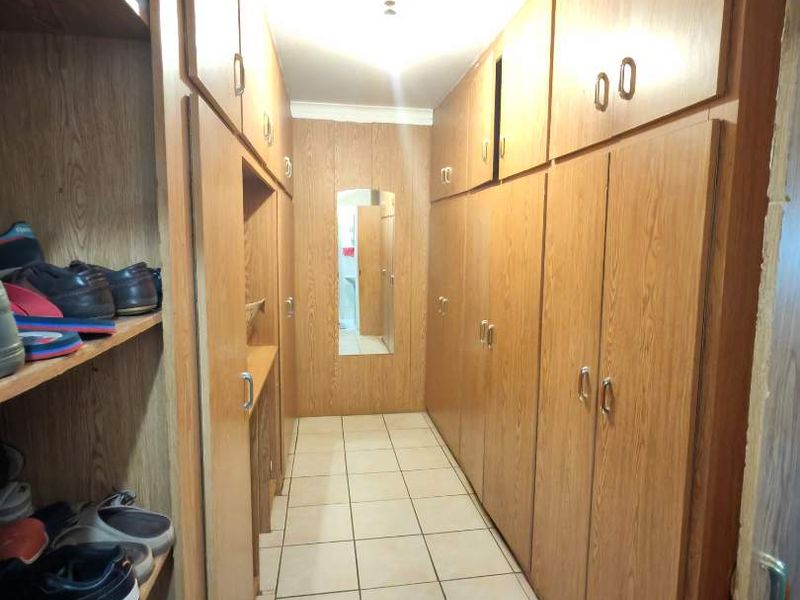 A functional hallway featuring extensive built-in wooden cabinetry for storage and tiled flooring throughout.