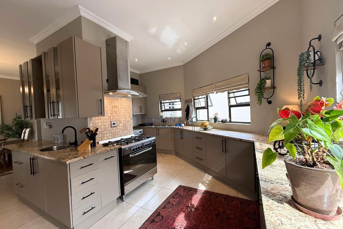 Modern kitchen featuring granite countertops, ample cabinetry, a stainless steel gas stove with extractor fan, and tiled flooring.