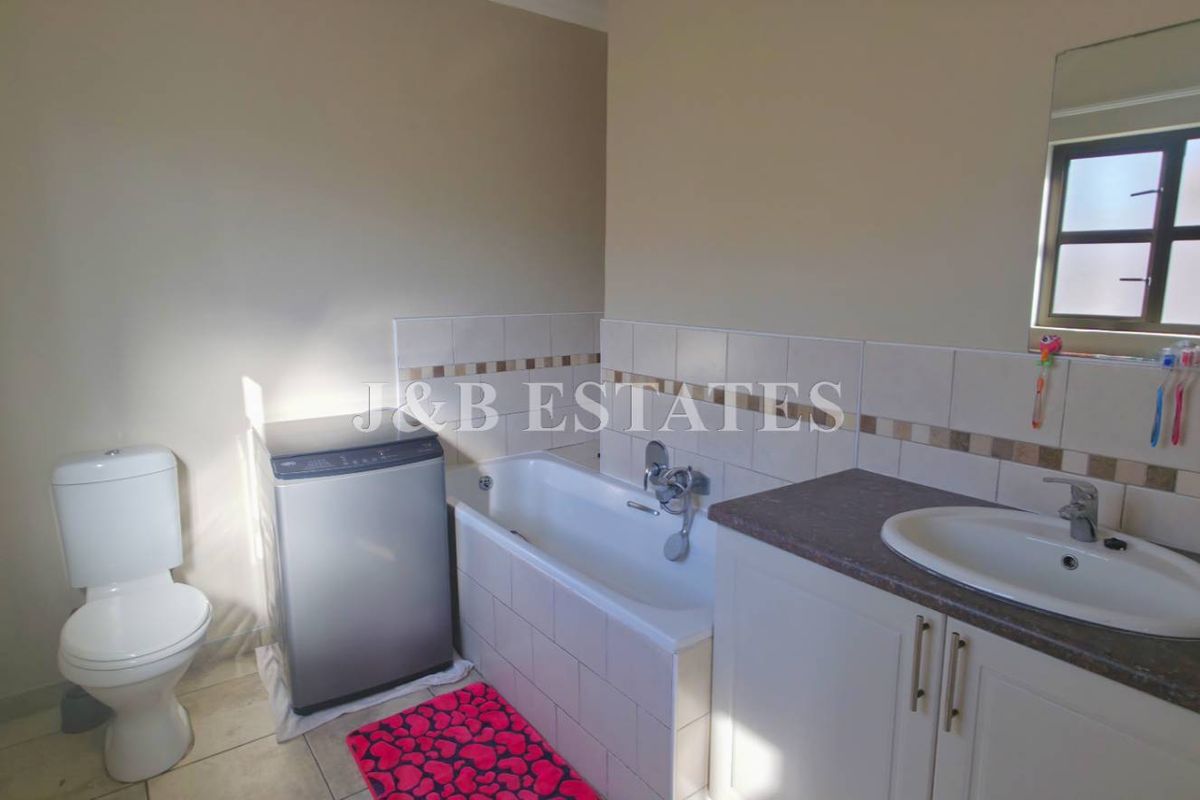 A functional bathroom featuring a built-in vanity with basin, a bathtub with shower mixer, and a toilet.