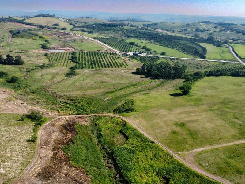 An expansive aerial view of a large farm property featuring rolling hills, cultivated orchards, open pasture land, and established access roads.