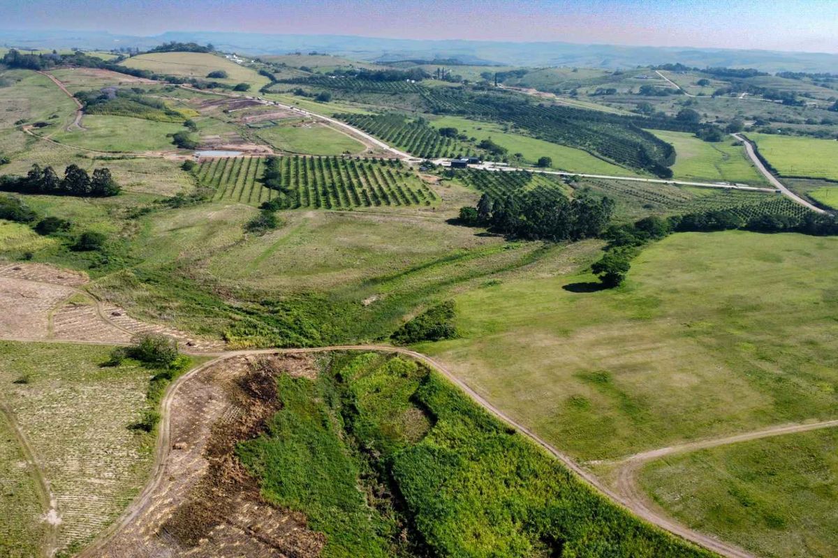 An expansive aerial view of a large farm property featuring rolling hills, cultivated orchards, open pasture land, and established access roads.