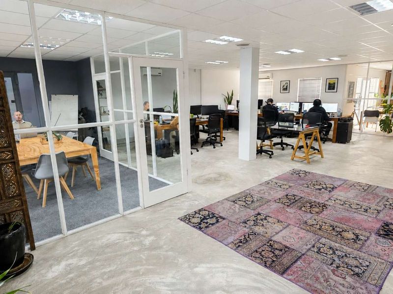 Open-plan office space featuring polished concrete floors, glass-partitioned meeting rooms, and a modern suspended ceiling with recessed lighting.