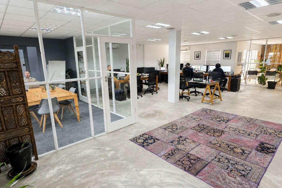 Open-plan office space featuring polished concrete floors, glass-partitioned meeting rooms, and a modern suspended ceiling with recessed lighting.
