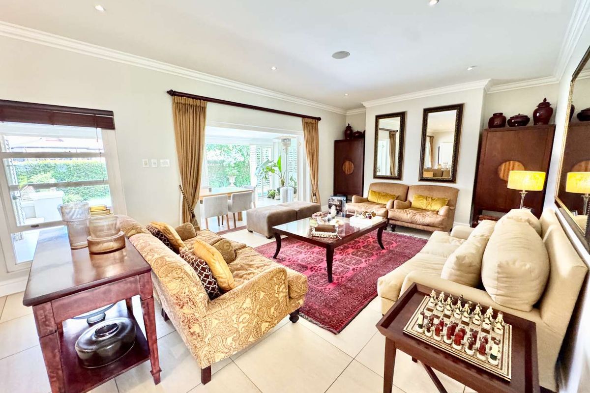Spacious living room featuring large format floor tiles, recessed downlighting, crown molding, and large sliding doors providing access to the outdoor patio area.