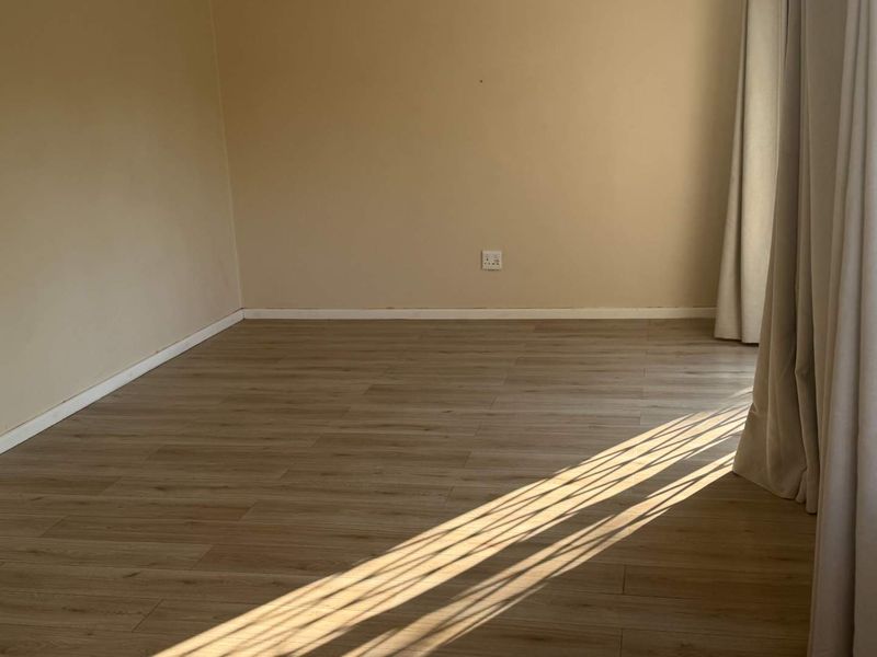 A bright, empty bedroom featuring modern light-toned laminate flooring and neutral wall finishes, ready for personalization.