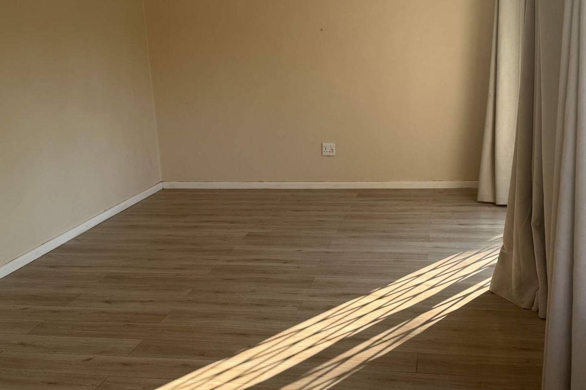 A bright, empty bedroom featuring modern light-toned laminate flooring and neutral wall finishes, ready for personalization.