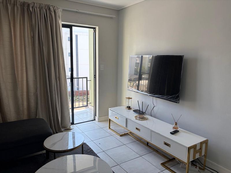 A bright living room featuring tiled flooring and a sliding glass door providing direct access to an outdoor balcony area.