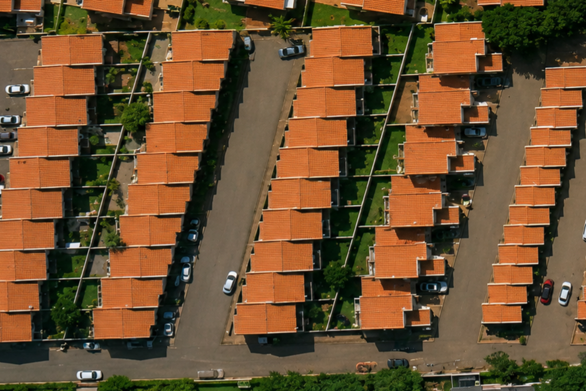 An aerial view of a townhouse complex featuring rows of units with terracotta tiled roofs and paved access driveways.