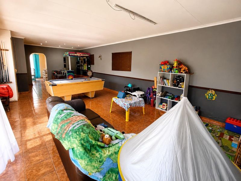 Spacious living area featuring tiled flooring and an archway leading to adjacent rooms, offering a versatile layout for family living.