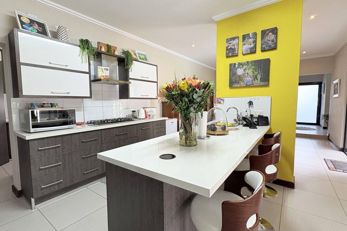 Modern kitchen featuring a central island with breakfast bar seating, built-in cabinetry, gas hob, and tiled flooring in an open-plan layout.