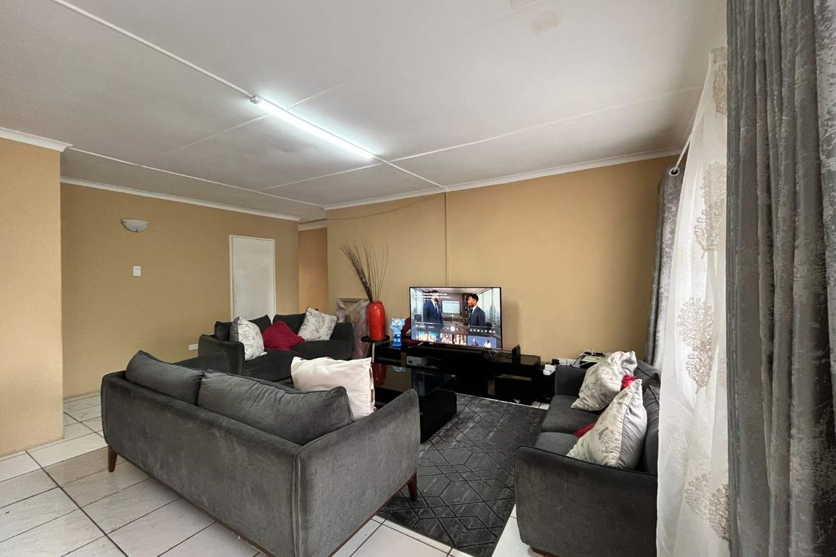 A living room featuring tiled flooring and a ceiling with visible panel joints and water staining, requiring cosmetic attention.