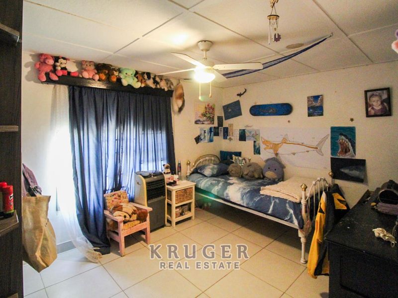 A bedroom featuring tiled flooring, a ceiling fan, and a drop ceiling. The room requires cosmetic updates to improve its overall condition.
