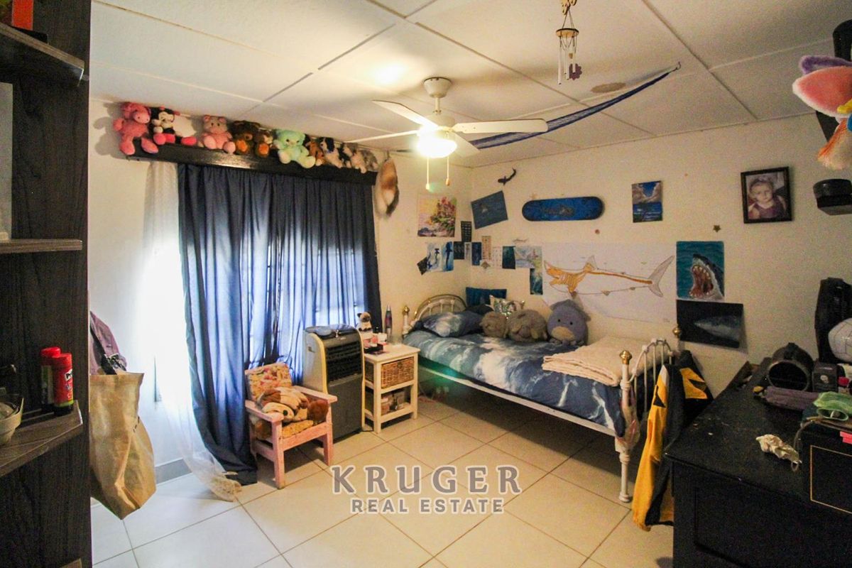 A bedroom featuring tiled flooring, a ceiling fan, and a drop ceiling. The room requires cosmetic updates to improve its overall condition.